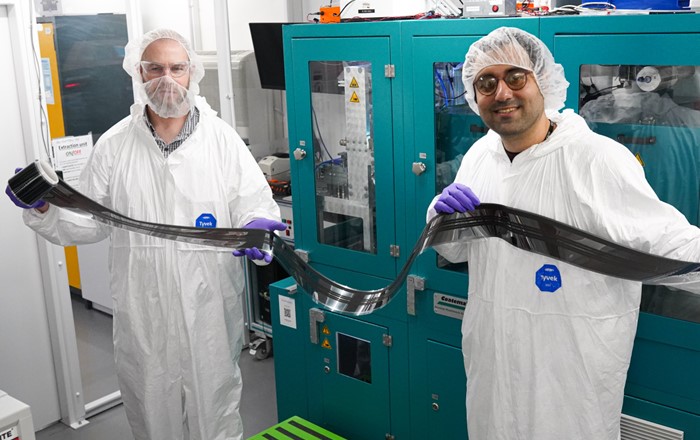 Dr David Beynon (Left) and Dr Ershad Parvazian (Right) wearing protective clothing and holding a sample of the new fully roll-to-roll (R2R) coated device.