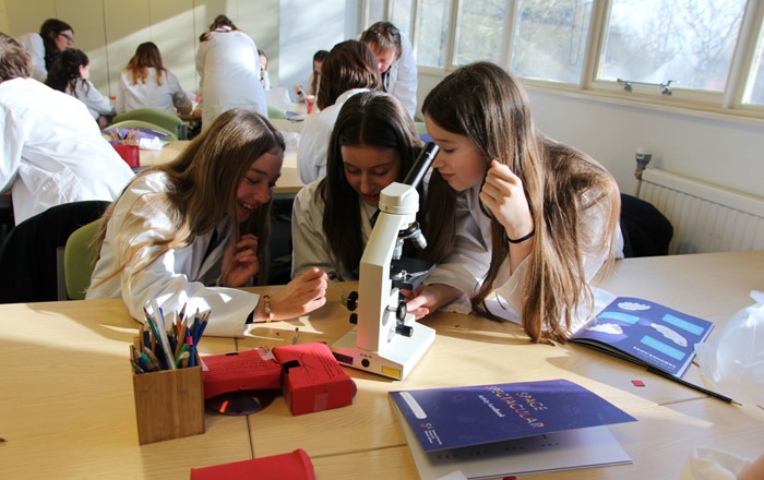 Three students doing an experiment using a microscope.