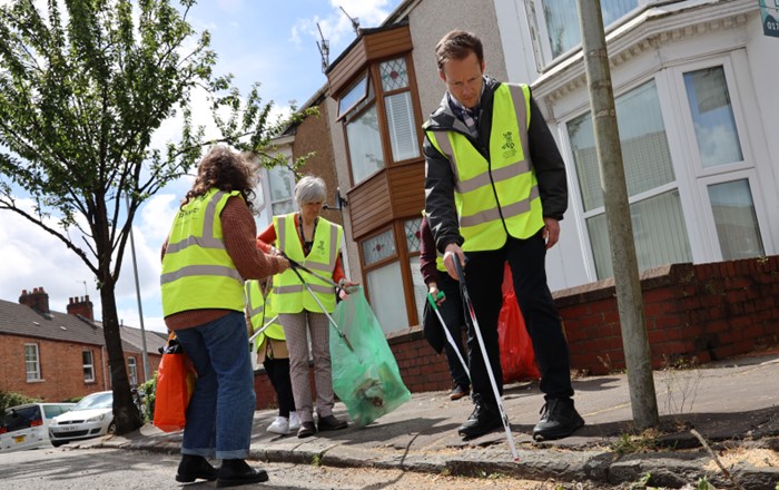 People in high-viz tabards picking up litter in a street