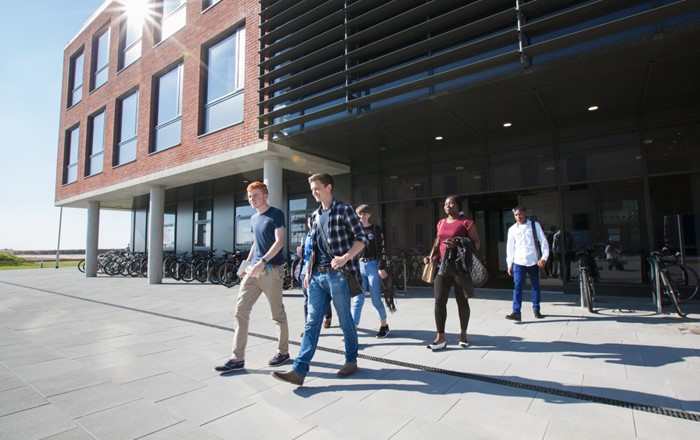 Group of students walking out from a modern building