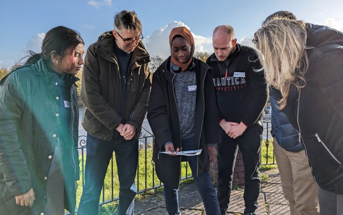 Group of people standing outdoors looking at a map.