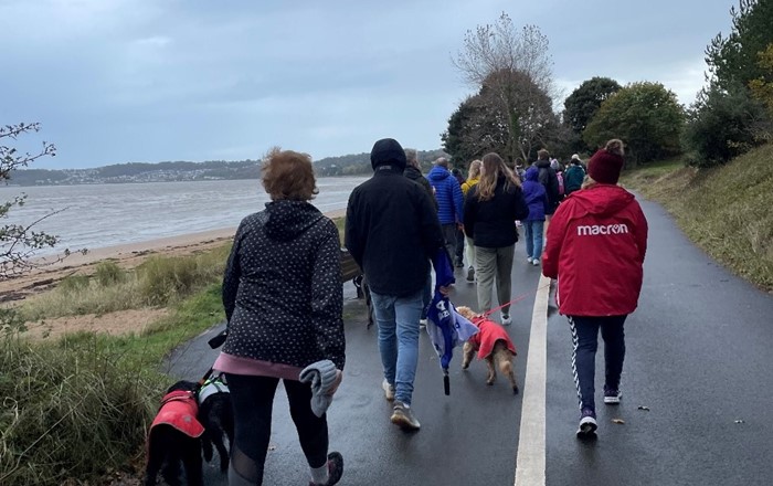 Group of people walking along a footpath near the sea