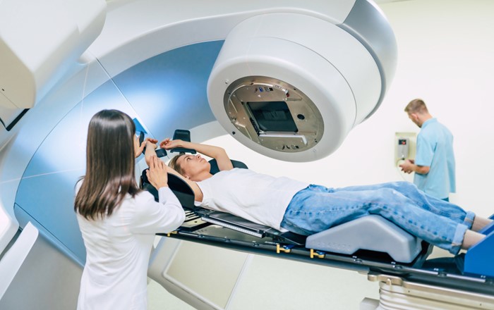 A stock photo of a woman undergoing radiation therapy using a linear accelerator.