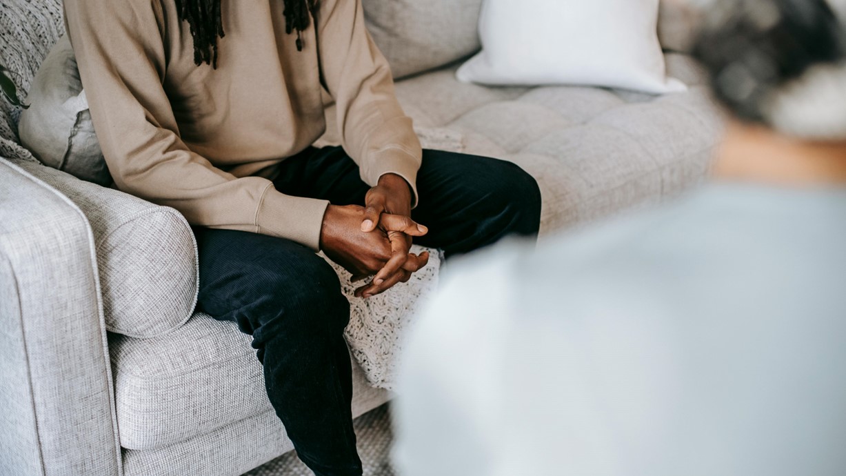 A man sitting on a couch opposite another person.