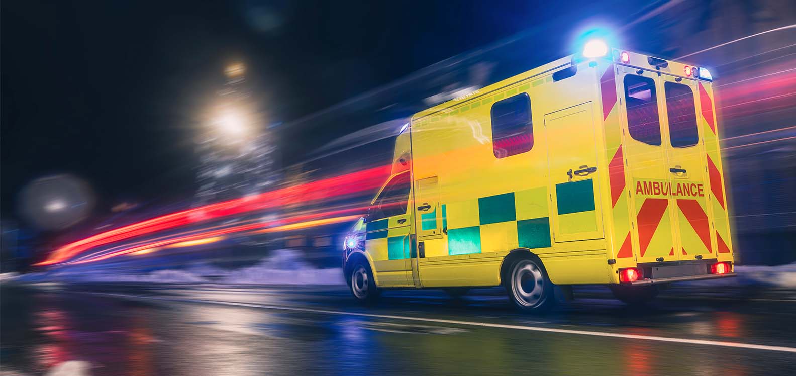 Ambulance driving at speed at night with blue lights on