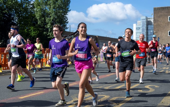 Smiling runners taking part in a race running along a road.