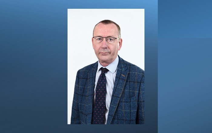 Head and shoulders photo of man white man wearing glasses dressed in shirt and tie