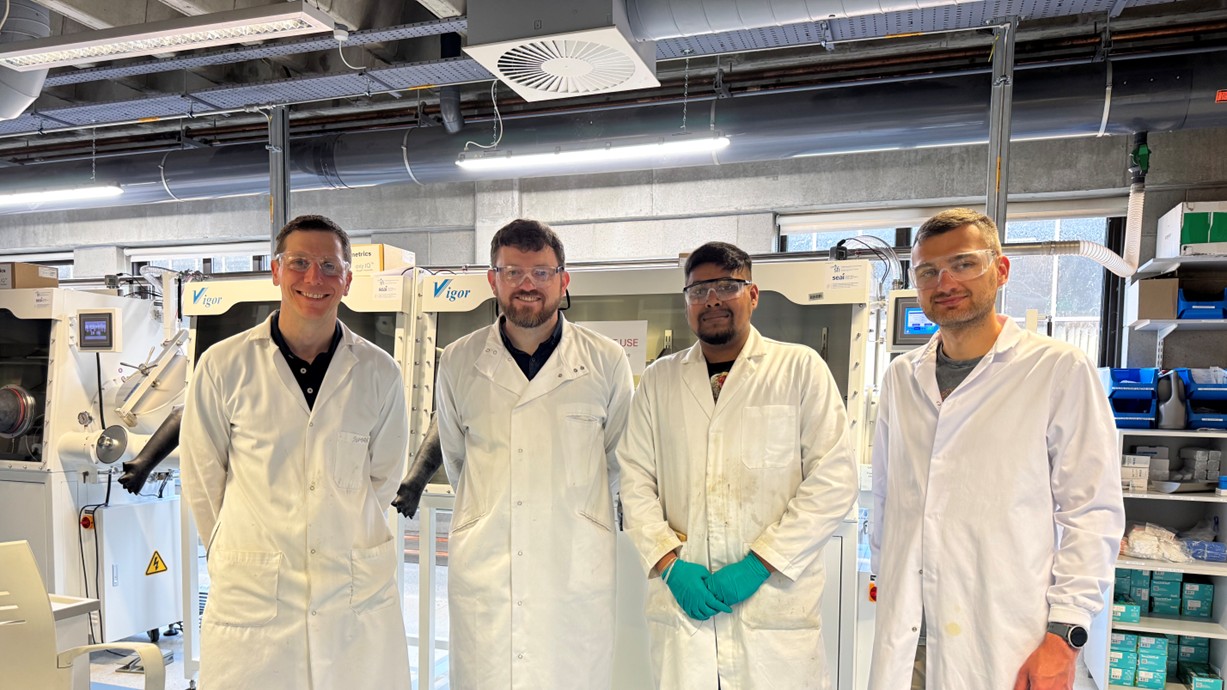 Four people standing in the battery lab at the University of Limerick during a project kick-off meeting. Each is wearing a white lab coat and protective glasses. From left to right: Professor Tadhg Kennedy (UL), Dr Ashley Willow (SU), Dr Mugilan Narayanasamy (UL), and Dr Marcin Orzech (SU).