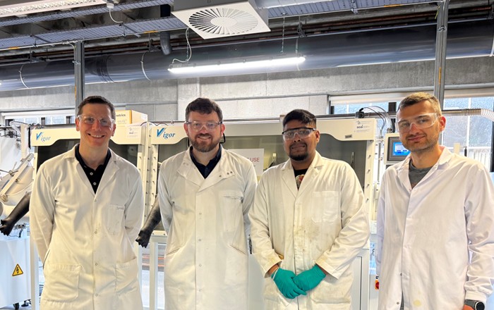 Four people standing in the battery lab at the University of Limerick during a project kick-off meeting. Each is wearing a white lab coat and protective glasses. From left to right: Professor Tadhg Kennedy (UL), Dr Ashley Willow (SU), Dr Mugilan Narayanasamy (UL), and Dr Marcin Orzech (SU).