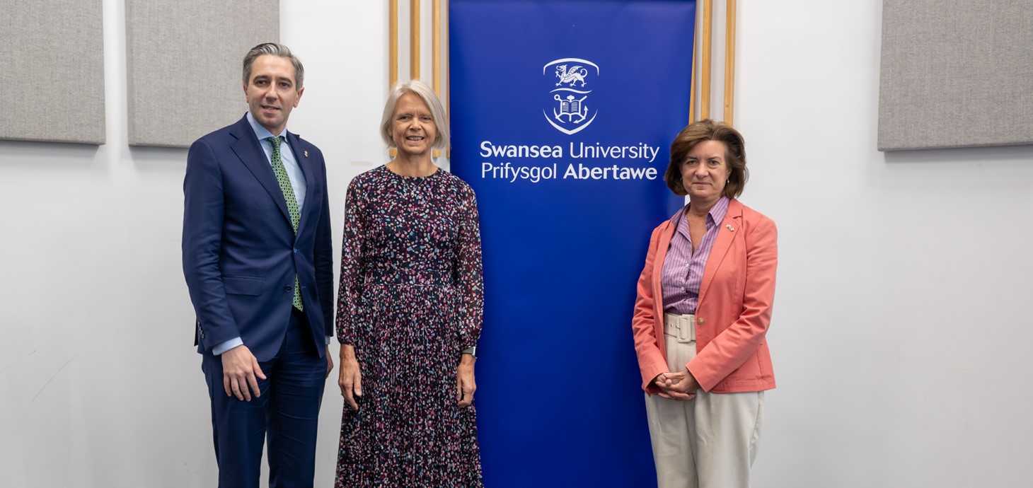 The Tánaiste, Simon Harris TD, Professor Helen Griffiths and First Minister of Wales, Eluned Morgan MS, at Swansea University. They are pictured standing in front of a Swansea University banner.