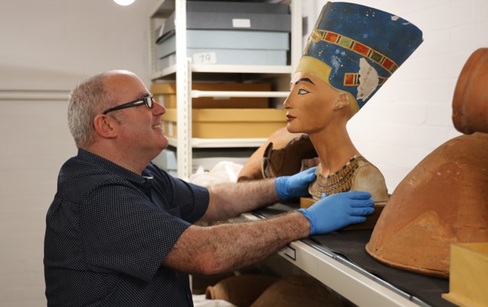 Man wearing gloves examining an Egyptian bust