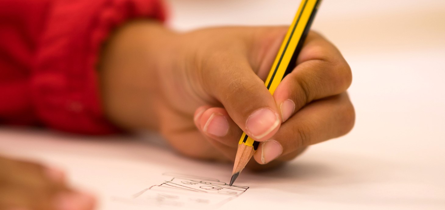 A close-up of a child's hand holding a pencil