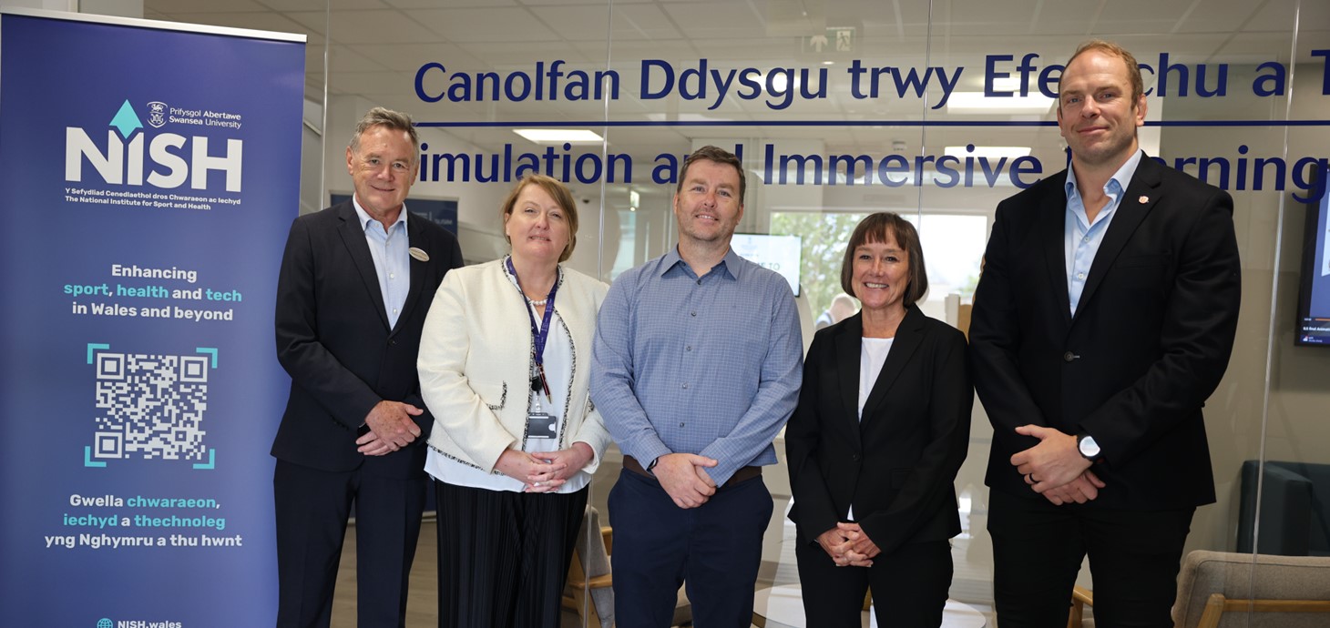 Five smartly dressed people standing in front of a glass partition alongside a pop-up banner