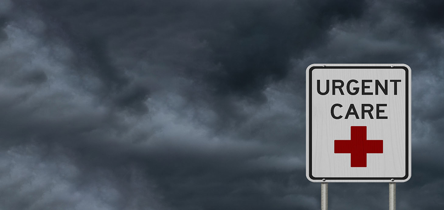 A rectangular white sign which has a red cross and URGENT CARE on it.