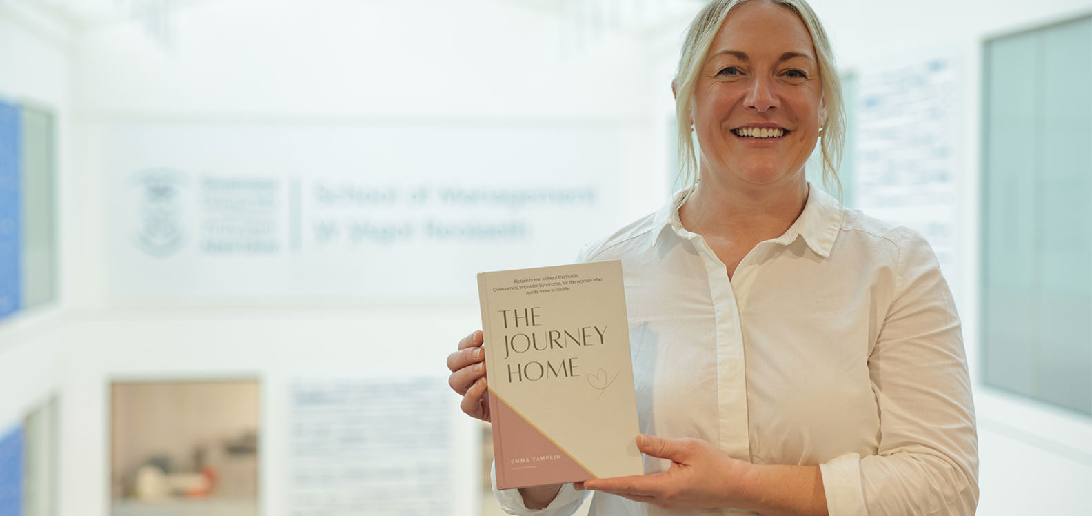 Smiling woman holding up a book