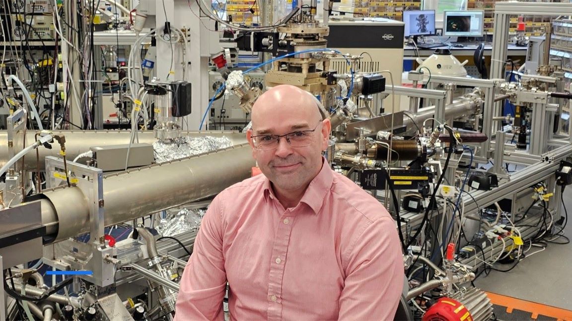 Man sitting in front of equipment in a physics laboratory