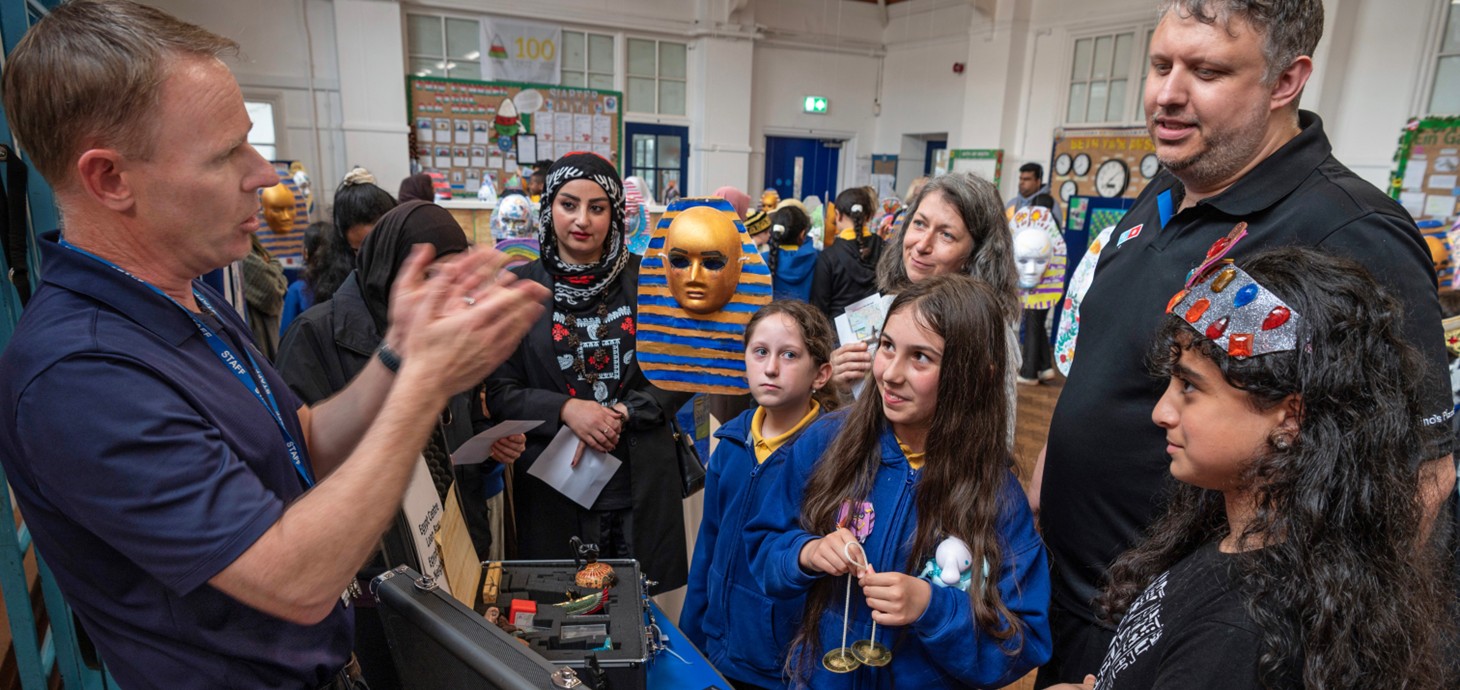 Schoolchildren and adults looking at an object in a classroom