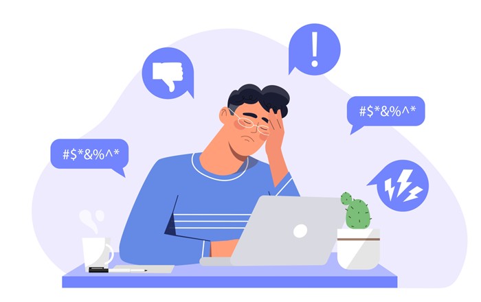Illustration of a frustrated person sitting at a desk with a laptop, surrounded by negative speech bubbles