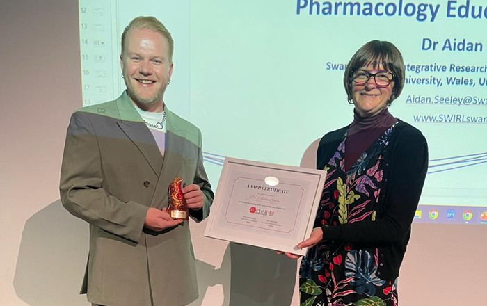 Man holding trophy alongside woman holding certificate.
