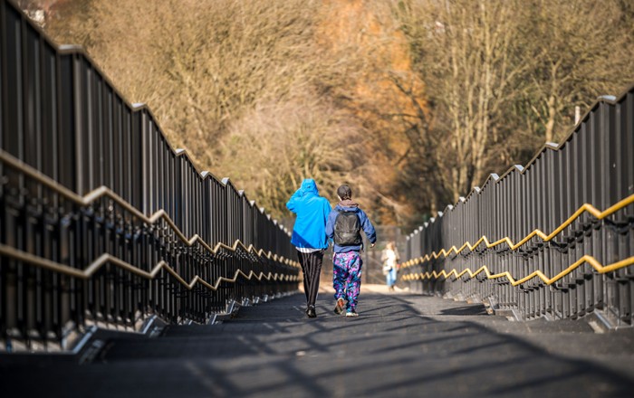 Two children walking away from camera along a bridge.