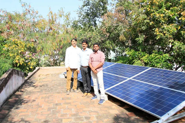 Three men standing by solar panels