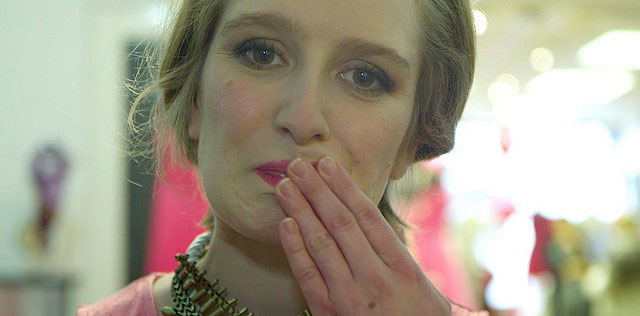 A woman wearing make up with her hand over her mouth