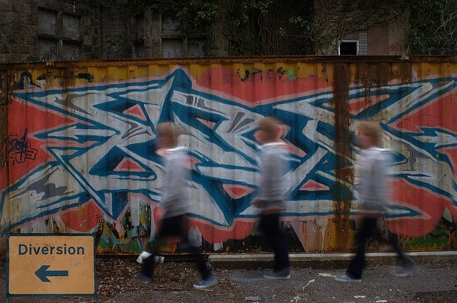 A blurred person walking past a graffiti wall