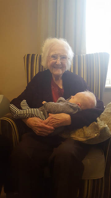 Older person, holding a baby in their arms