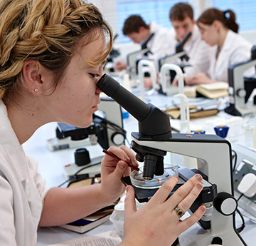 Bioscience student looking down at microscope