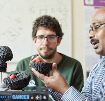 Dr Gibin Powathil explaining to a student about monitoring cancer growth in the brain