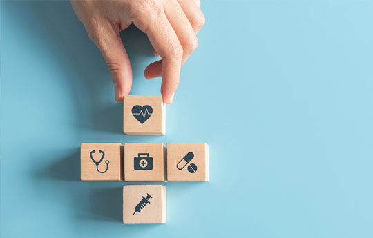 a hand placing 5 wooden blocks with health images on them
