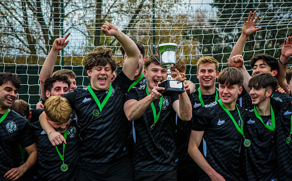 A group of students holding their cup in the air after winning their Intramural 5-a-side football tournament 