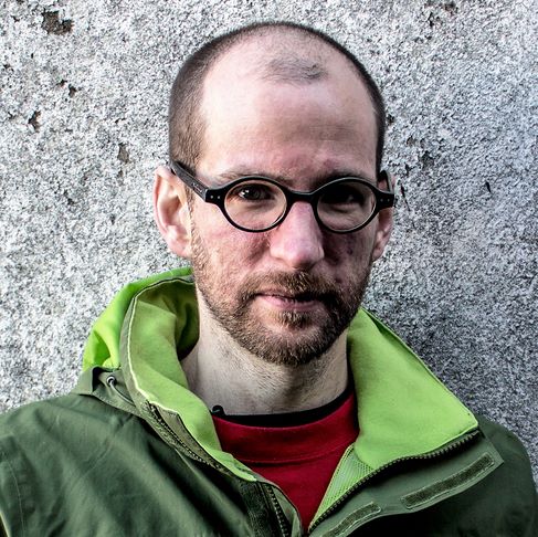 Dr Alan Kellermann in green jacket in front of grey wall.