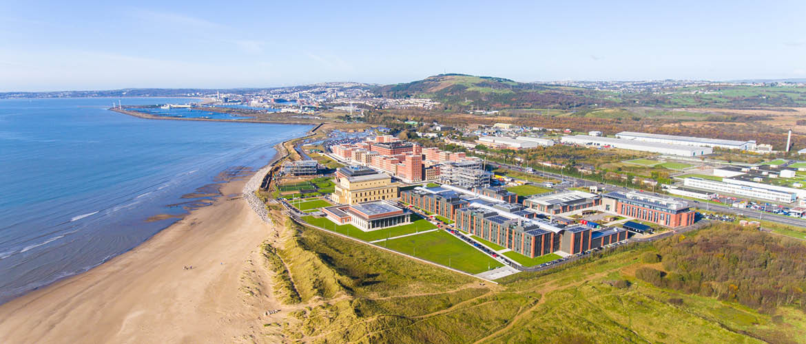 An aerial view of Bay Campus, with the sea stretching into the horizon.