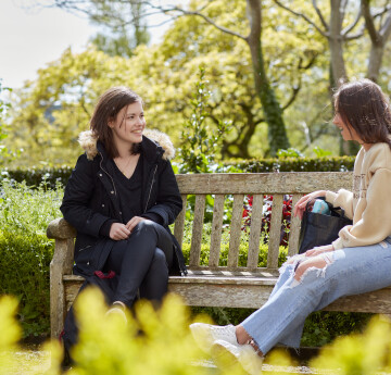 Two students chatting while sitting on a bench