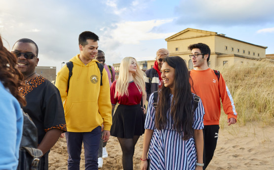 A group of students walking on the beach at Bay Campus