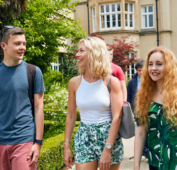 Three students walking passed the Abbey building at Swansea University