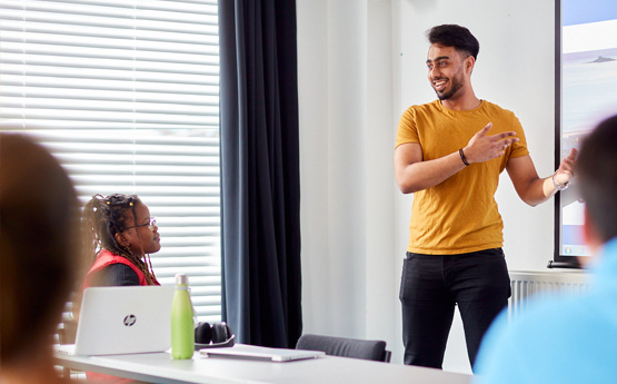 Male student presenting in front of a whiteboard