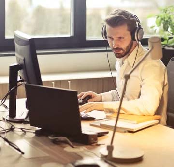 A man working at a computer, wearing a set of headphones