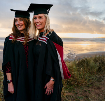 Two graduates at sunset by the beach