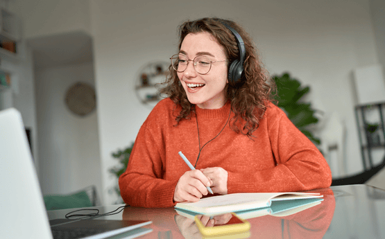 A student watching a webinar and taking notes. 