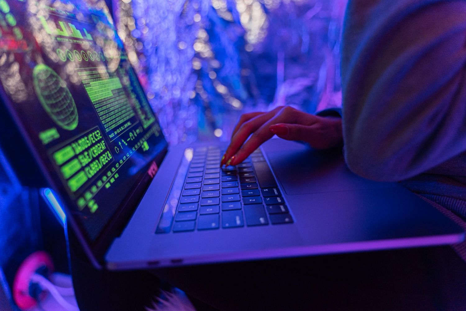 A person typing on a laptop with coding on the screen