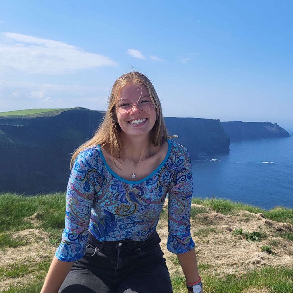 Student sitting in front of Rhossili on a sunny day.