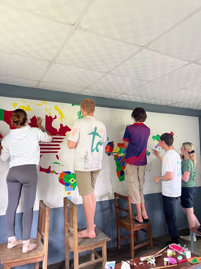 Group of volunteer students painting a classroom wall