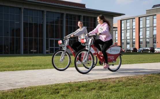 Two students cycling together on Santander cycles