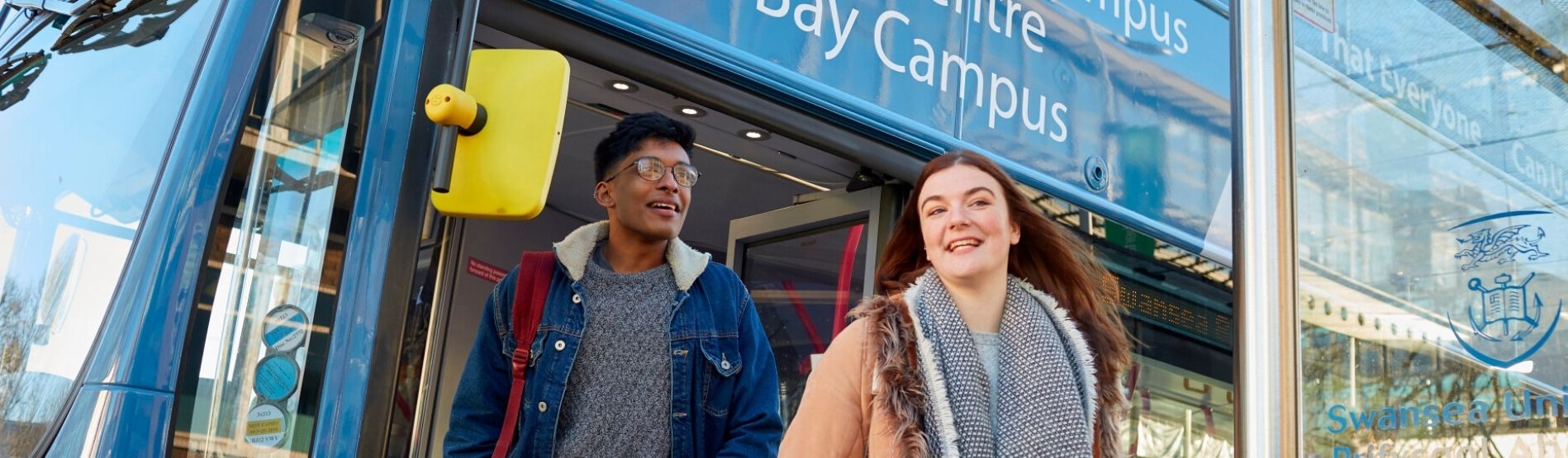 A male and female student getting off a First Cymru bus