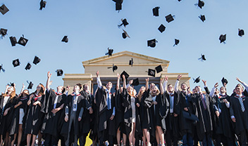 A group of students at graduation throwing their hats in the air in celebration