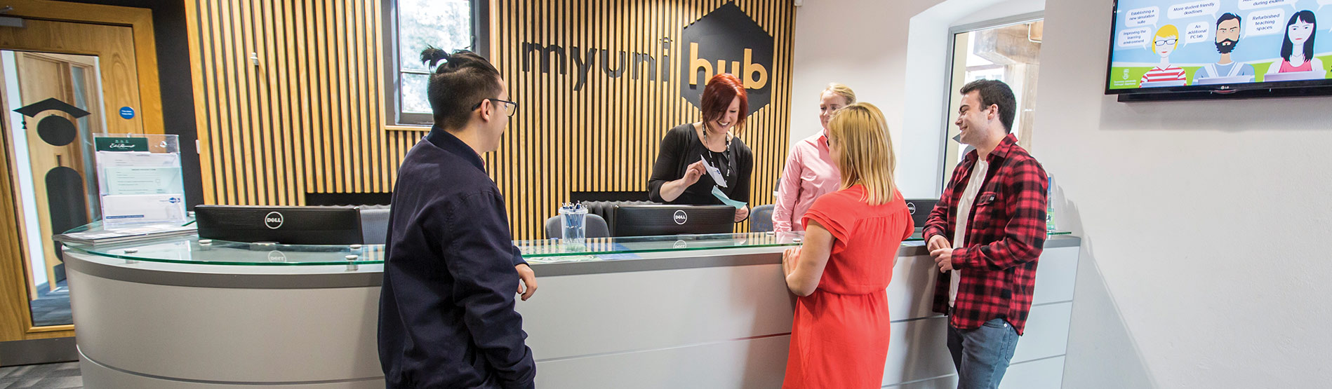 Students talking to receptionist at the Uni Hub of Swansea University.