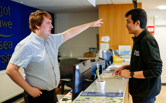A colleague behind a desk giving a staff member advice