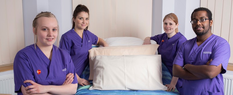 nursing students standing by bed. 
